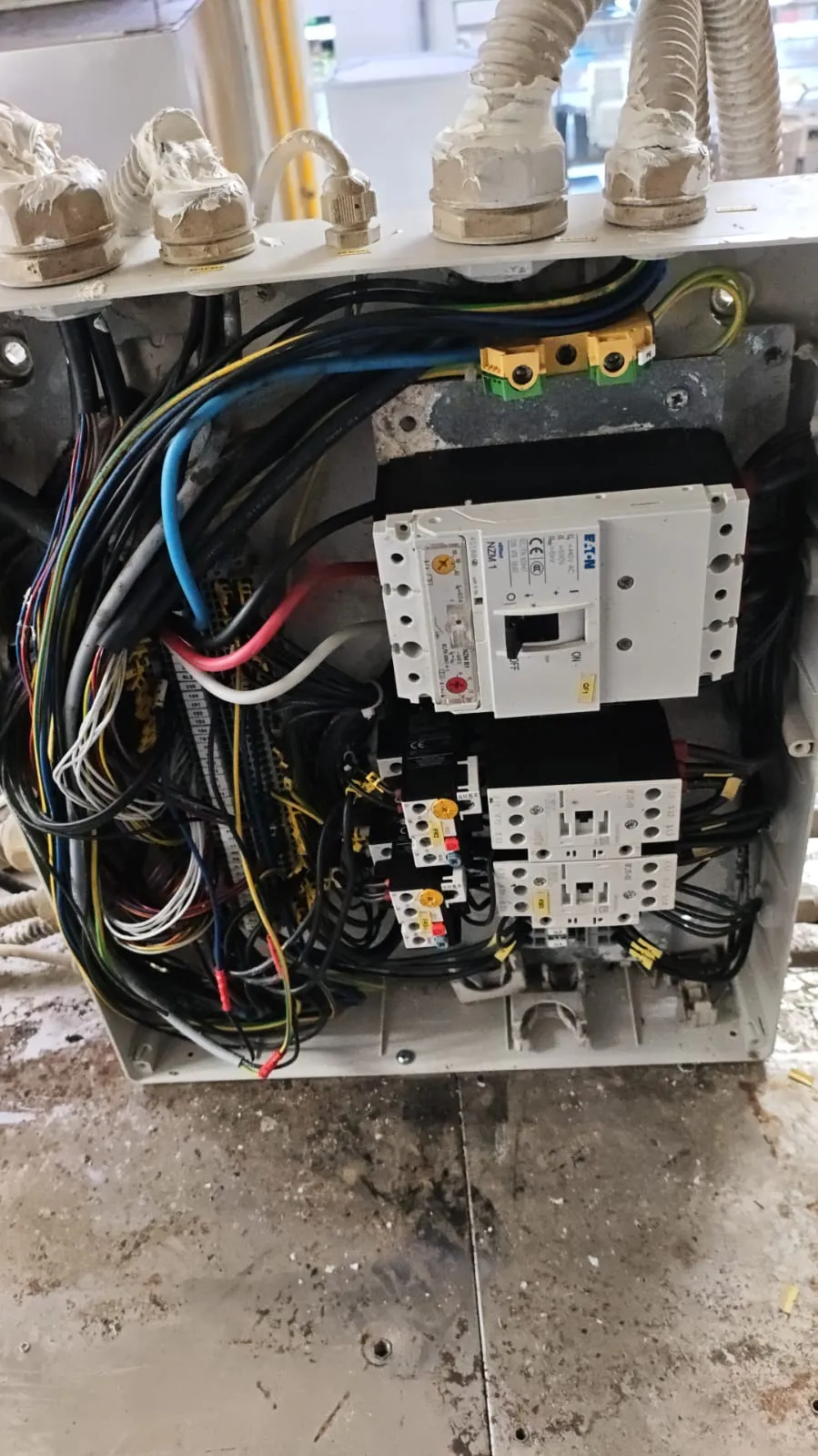 Quadro elétrico aberto com disjuntor Eaton NZM1, contatores, relés térmicos e feixes de cabos coloridos