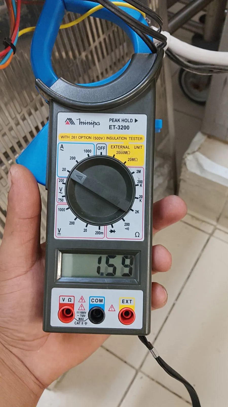 Alicate amperímetro Minipa ET-3200 envolvendo um cabo, com 1,59 no visor